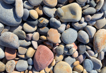 Stones on beach. Decorative texture of stones. Sea stones background. Colored stone on coastline..
