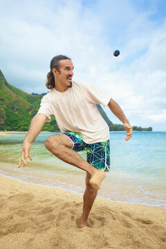 A man plays with his hackey sack in the sand at the water's edge; Hawaii united states of america