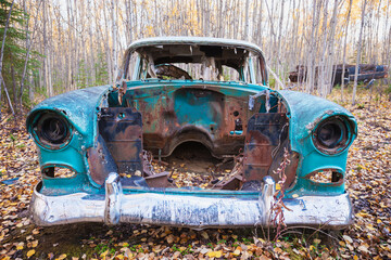 Old derelict car sitting in a forest in autumn; Nenana alaska united states of america