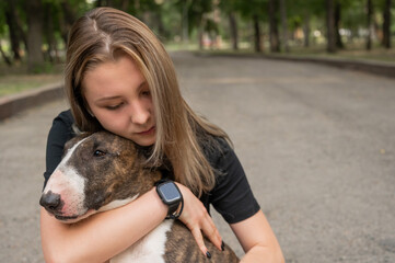 Portrait of caucasian woman hugging her bull terrier dog outdoors. 