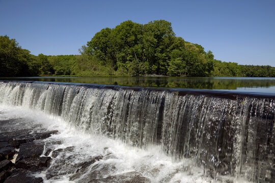 Massachusetts, Northbridge, A Waterfall At The Edge Of Very Calm Lake With Reflection.