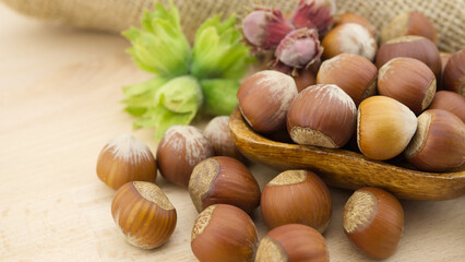 Hazelnuts beside the jute sack on wooden table