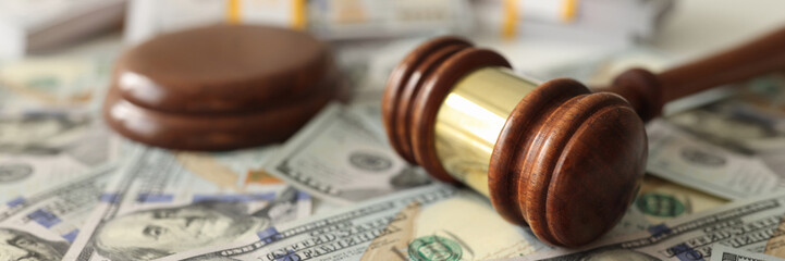Judge gavel on dollar banknotes background, shallow depth of field.