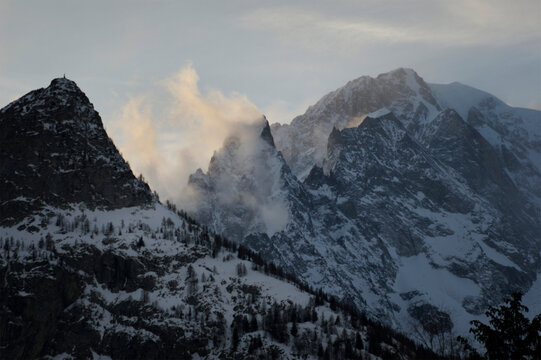 Mont Blanc as seen from Aiguille du Midi, with rugged mountain peaks and clouds backlit by sunlight; Chamonix, France - Powered by Adobe