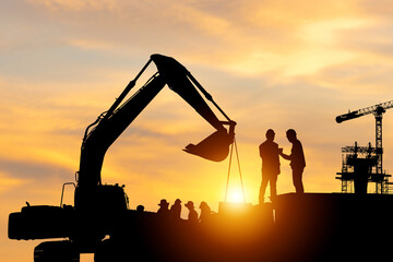 Silhouette of Engineer and worker checking project at building site background, construction site at sunset in evening time