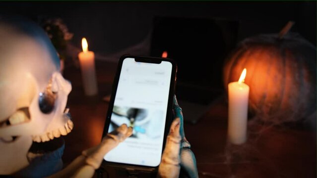 Funny terribly scary death with modern smartphone immersed in the internet space of social network applications. Technology and media, Halloween celebration vibe.