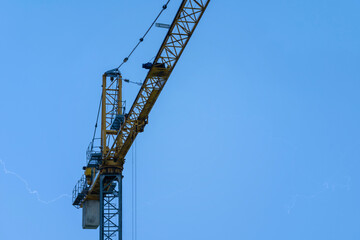 Crane and lightning, powerful thunderbolt. Weather risk assessments for the construction industry and built environment