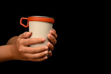 Hands holding stainless steel travel mug on black back ground. Tumbler beverage container and Eco friendly lifestyle