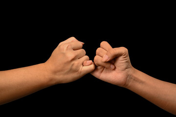 Two hands hooking each other little finger on black background, symbol of promise or pardon