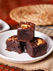 Chocolate pound cake. A piece of cake is cut into pieces and served with chocolate ganache cream. Brown wooden background. Dark mood.