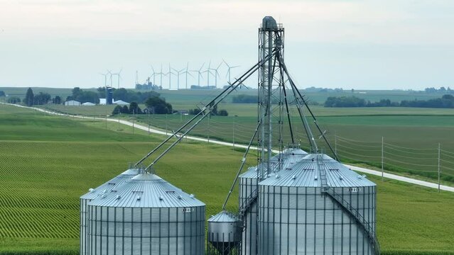 Grain elevator in Midwest USA. Aerial shot with telephoto zoom lens. Wind turbines and corn fields in background.