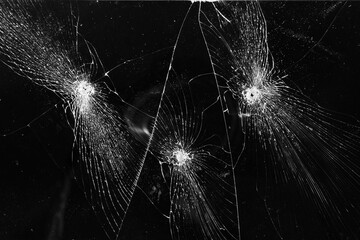 Broken glass with bullet holes texture on black background