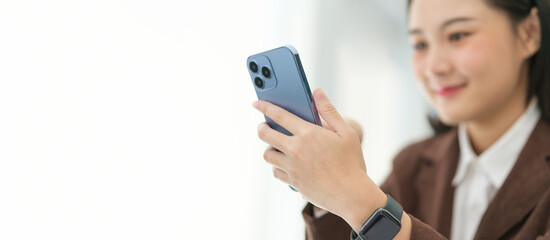Cropped shot of cheerful businesswoman sitting and using smart phone.