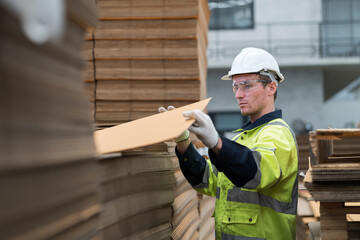 Male warehouse worker working and inspecting quality of cardboard in corrugated carton boxes warehouse storage