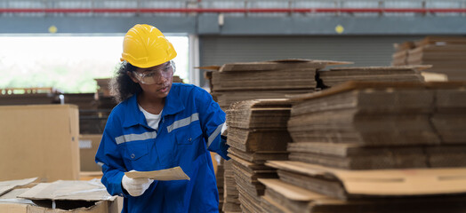 Female warehouse worker working and inspecting quality of cardboard in corrugated carton boxes...