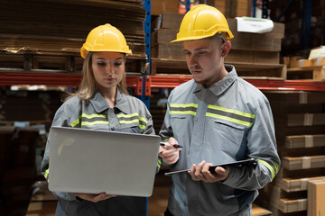 Male and female warehouse worker working and inspecting quality of cardboard in corrugated carton boxes warehouse storage. Warehouse workers inspecting quality of barcodes on shelves pallet