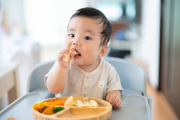 離乳食後期でをつかみ食べをしてご機嫌な生後9か月の赤ちゃん