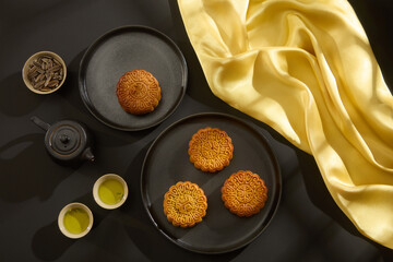 Overhead view of tea table party with mooncakes on round dishes and yellow silk cloth. Advertising image for the above moon cake company on the occasion of the traditional Mid-Autumn Festival