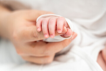 Newborn baby's gentle grasp on mother's finger evokes emotions. Concept of maternal bond and trust