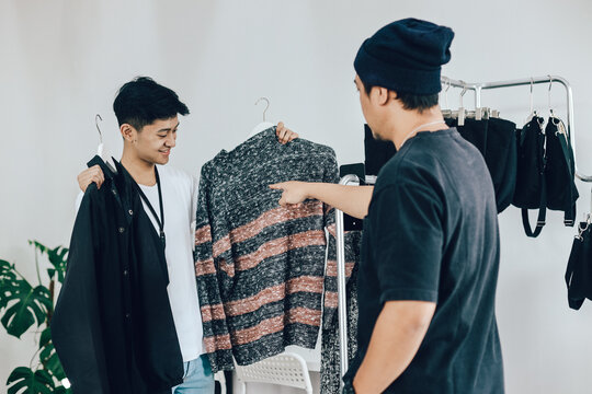 Male customer shopping in clothing store, retail sales associate helps with advice.