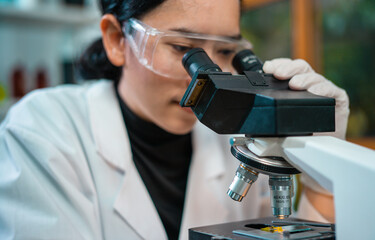Medical Research Laboratory. Female Scientist Using Microscope to analyze substance or liquid.