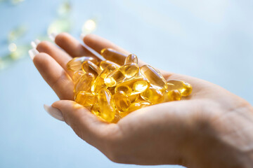 Close-up medicine yellow transparent pills, omega 3 fish oil capsules, vitamin D. Many yellow transparent capsules in hand close-up. The concept of health, vitamins, and medicine
