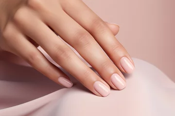 Foto op Plexiglas Glamour woman hand with nude nail polish on her fingernails. Nude shade nail manicure with gel polish at luxury beauty salon. Nail art and design. Female hand model. French manicure. © Artinun