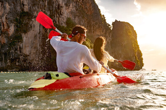 Happy young couple walks on kayak or canoe at sunset sea bay. Phranang Railay beach, Krabi, Thailand.