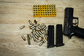 Handgun and bullets and mags lying on a wooden table