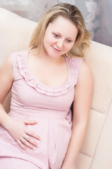 Naklejka premium Pregnancy Concepts. Winsome Romantic Caucasian Pregnant Blond Female Resting on Couch