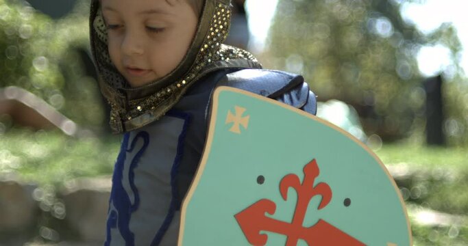 Little boy wearing traditional medieval costume hitting with sword and holding shield captured in high-speed 800 fps, speed ramp