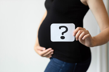 a pregnant woman holds a card with a question mark in her hand, gender party, determining the gender of the child, choosing the baby's name