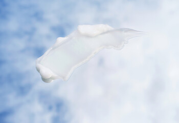 Smear of moisturizing cream against the background of sky and clouds, top view.