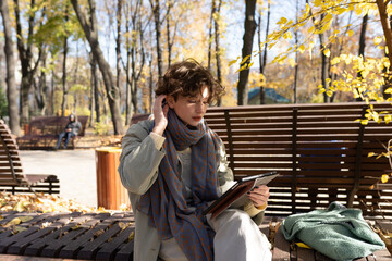 Happy teenage girl in autumn park on video call through laptop