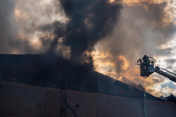 Severe fire in a storage factory. There was a fire in a warehouse. The flames engulfed the roof of the building. Burning produces heavy smoke. - 647552252
