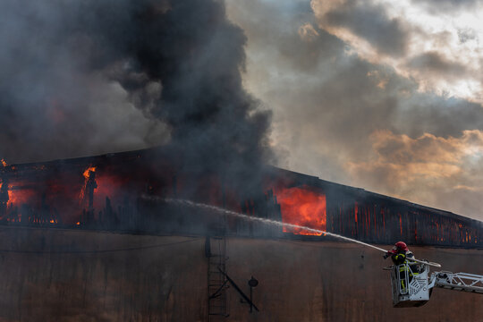 Severe fire in a storage factory. There was a fire in a warehouse. The flames engulfed the roof of the building. Burning produces heavy smoke.