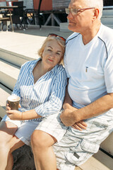 An elderly couple is sitting in a cafe on the terrace, a man hugs a woman