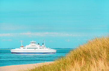 Summer scenery from Sylt island with boat navigating in North Sea, Germany