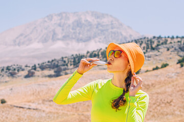 Pretty young woman biting on a energy sportive gel drink after a good hike in high mountains