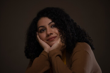 Fototapeta premium Close-up portrait of a woman with hands on cheek looking away and thinking