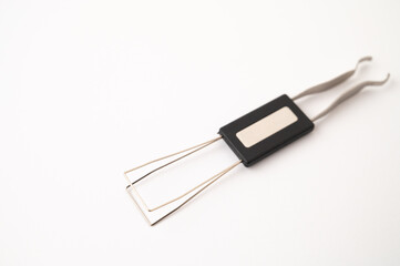 Close-up of a 2 in 1 stainless steel keycap and switch puller tool on a white background. Copy space.