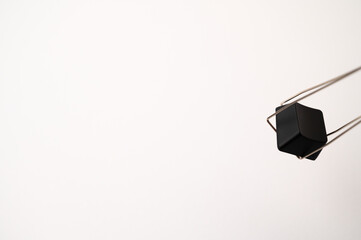 A close-up of a detached mechanical keyboard keycap hanging in a stainless steal keycap and switch puller tool on a white background. Copy space.
