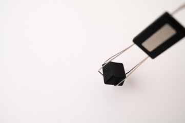 A close-up of a mechanical keyboard keycap placed inside a keycap and switch puller tool on a white background. Copy space.