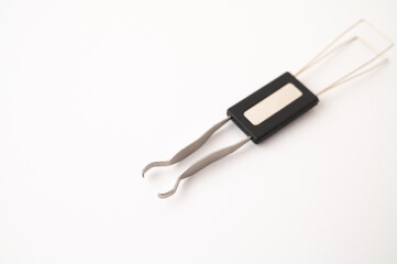 Close-up of a 2 in 1 stainless steel keycap and switch puller tool on a white background. Copy space.
