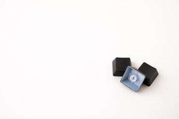 A close-up of a pile of three detached mechanical keyboard keycaps on a white isolated background. Copy space.