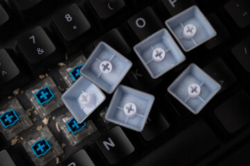 Close-up of a dirty mechanical keyboard with blue switches, with some keycaps removed and lot of debris visible.