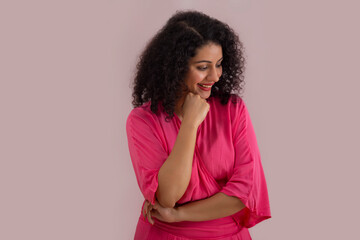 Beautiful woman in pink outfit looking down with hand on chin