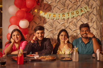 Friends celebrating birthday of their friend at restaurant 