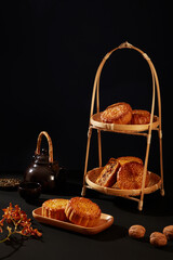 Two-tier bamboo basket with some delicious mooncakes decorated on over black background. Chinese...
