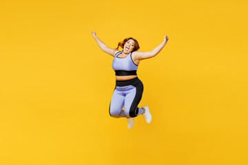 Fototapeta na wymiar Full body carefree young chubby plus size big fat fit woman wear blue top warm up training jump high with outstretched hands isolated on plain yellow background studio home gym. Workout sport concept.